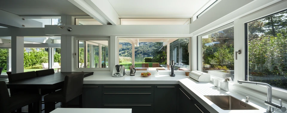 Cuisine moderne ouverte avec îlot central, comptoirs en quartz blanc, armoires laquées anthracite