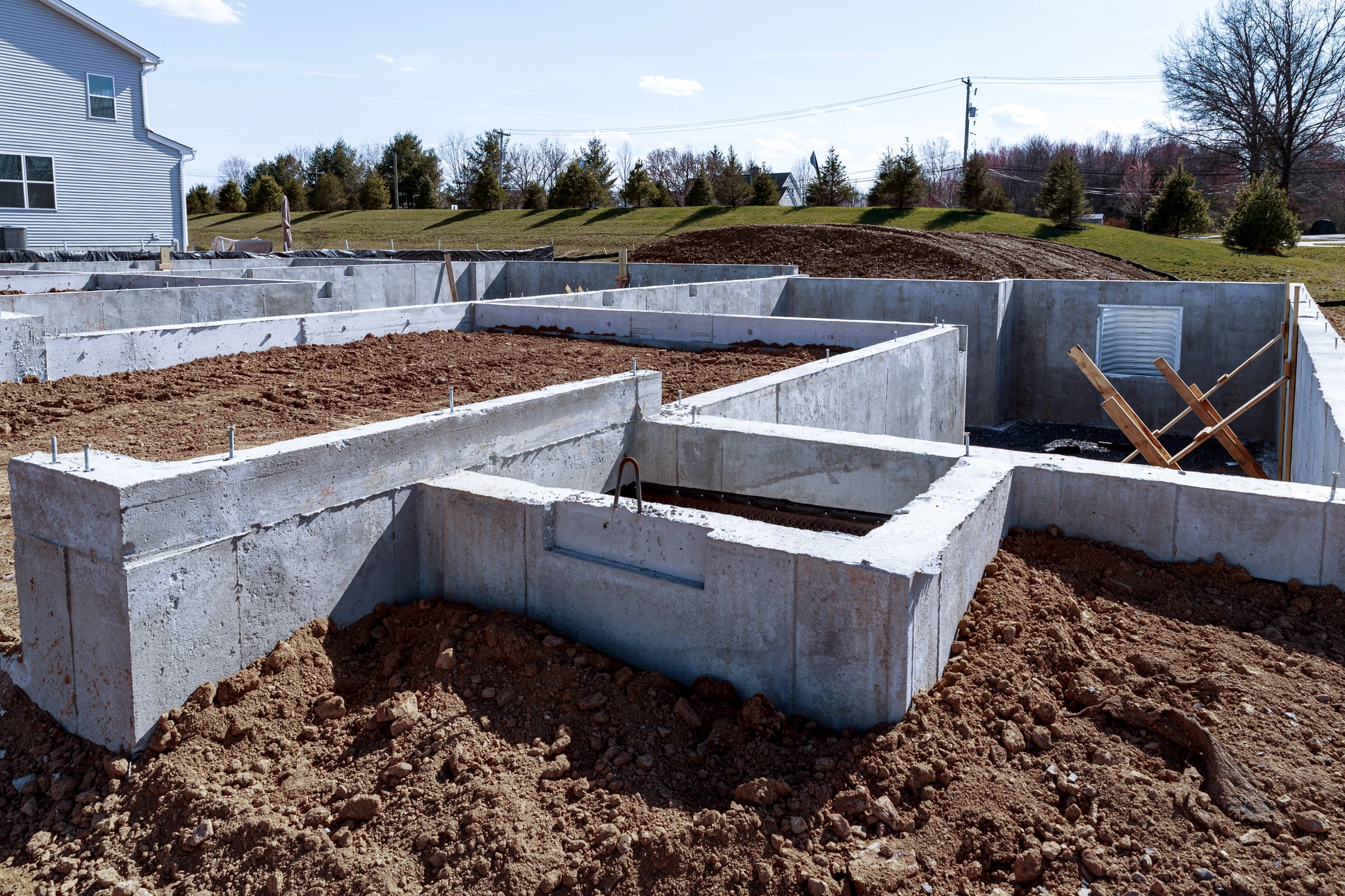 Chantier de construction extérieur avec ouvriers en gilets haute visibilité coulant du béton depuis une toupie bétonneuse rouge