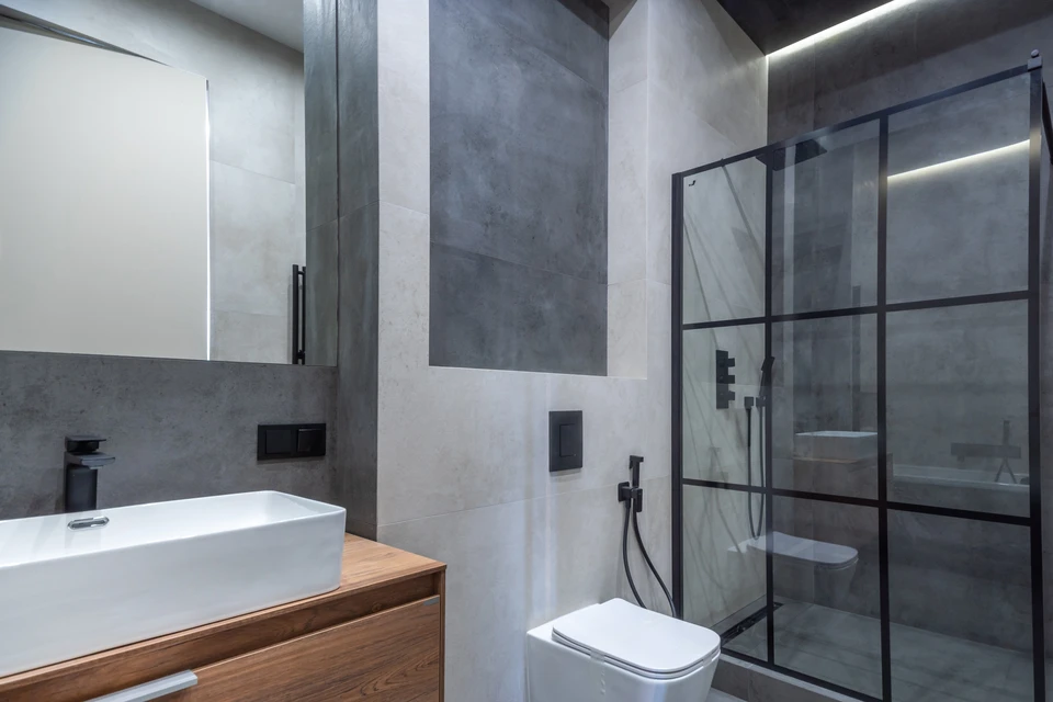 Cuisine moderne haut de gamme avec îlot central en granit moucheté gris-blanc, armoires en bois sombre, électroménagers professionnels en acier inoxydable