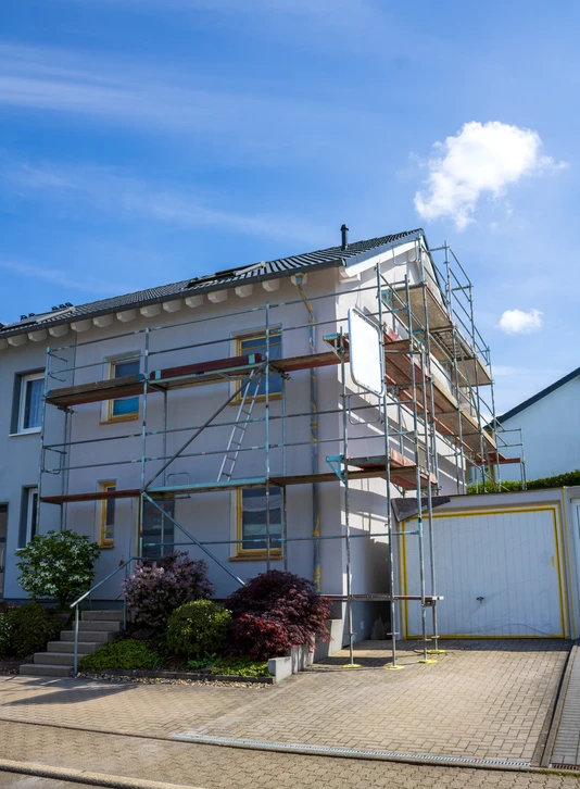 Ouvrier en bâtiment appliquant du mortier ou enduit sur un mur avec une taloche en plastique orange